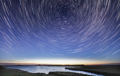 Time-lapse photography of stars above the water at night
